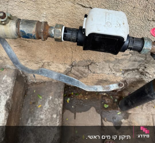 צינור מים עם ברז ומונה על קיר חיצוני